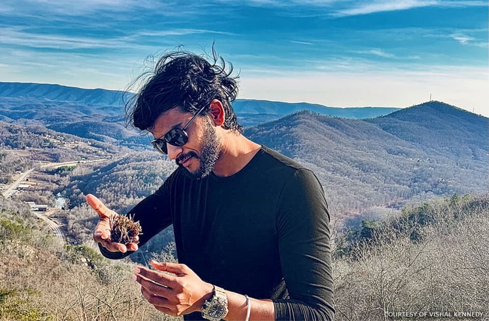 Vishal Kennedy conducting field research in a mountainous landscape.